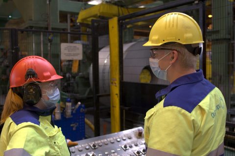 Kaksi suojakypäräpäistä työntekijää Outokummun tehtaalla Oikotien ja Outokummun kesätyövideossa