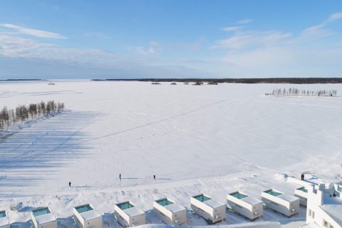 Jäätynyt meri ja lasikattoiset lomahuvilat ilmasta kuvattuna Kemin Matkailun videotuotannossa