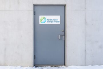Keminmaan Energian ja Veden logo kyltissä betonirakennuksen teräsovessa