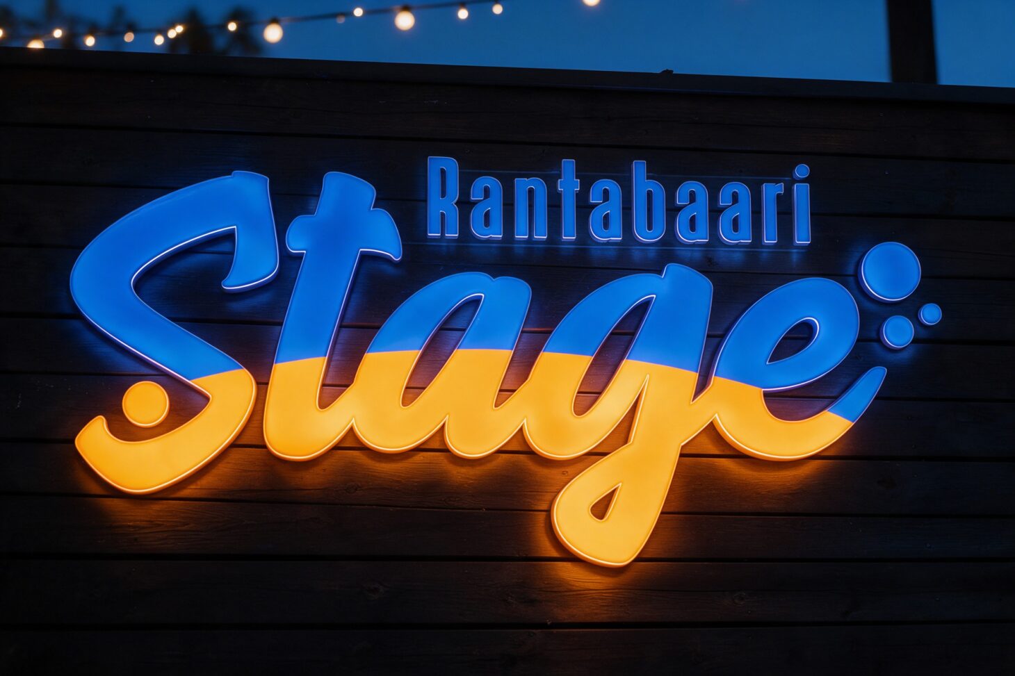 Rantabaari Stagen logo sinisenä ja keltaisena valomainoksena tummassa puuseinässä