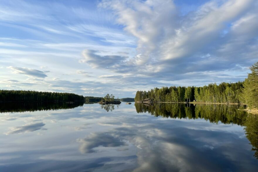 Pilvet heijastuvat tyyneen j&auml;rveen kes&auml;ll&auml;