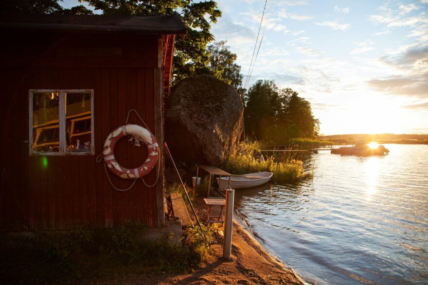 Punainen ranta-aitta, soutuvene ja tyyni vesi auringonlaskussa