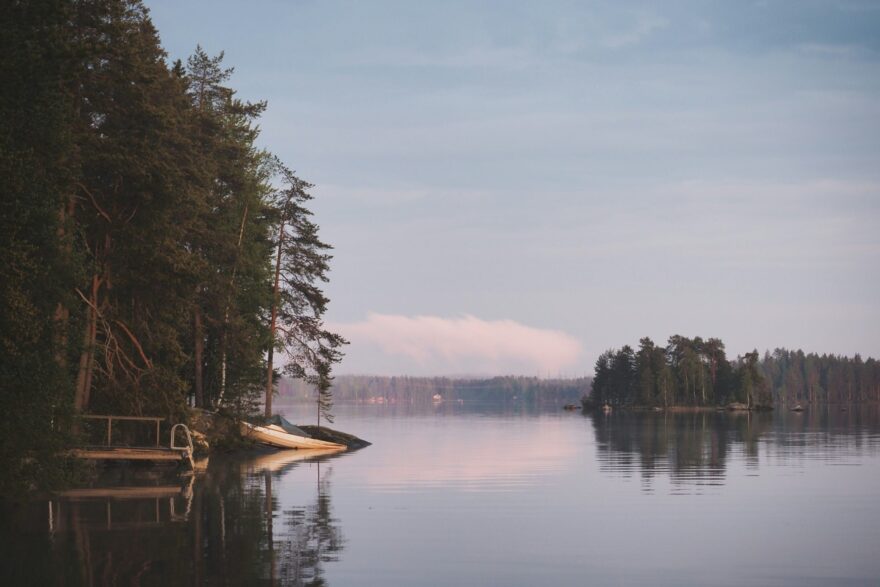 M&auml;ntyinen ranta, laituri ja vene tyynen j&auml;rven rannalla iltavalossa