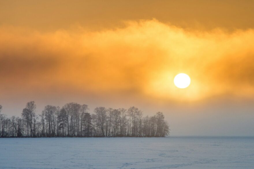 Aurinko nousee sumuisen talvimaiseman yll&auml;