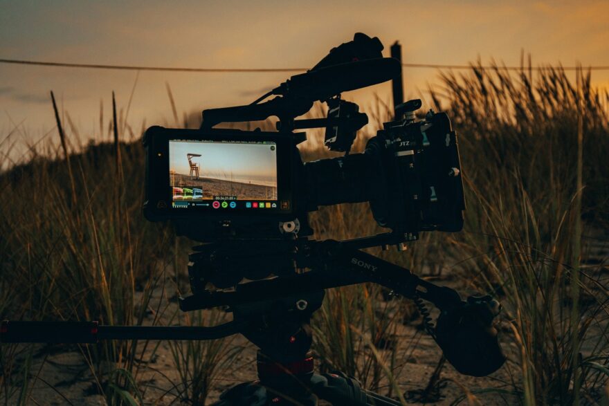 Videokamera jalustalla kuvaa rantaa auringonlaskun aikaan