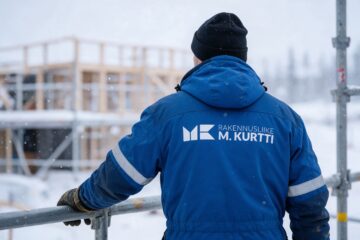 Rakennusliike M. Kurtin logo työtakin selässä työmaalla